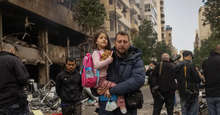 ইসরাইলি হামলায় ক্ষতিগ্রস্ত ভবনের পাশ দিয়ে মেয়েকে নিয়ে স্কুলে যাচ্ছেন এক পিতা